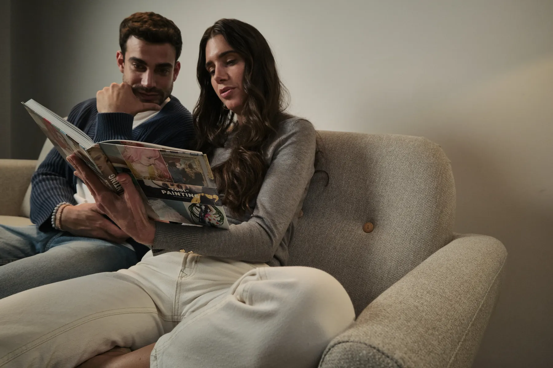 Pareja hojeando un libro en el sofá