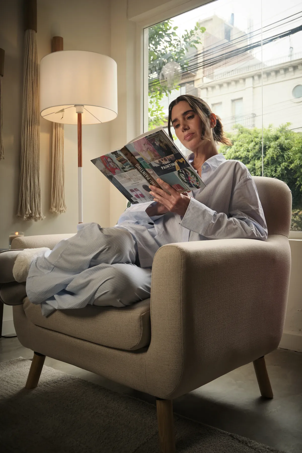 Mujer leyendo en sillón junto a la ventana