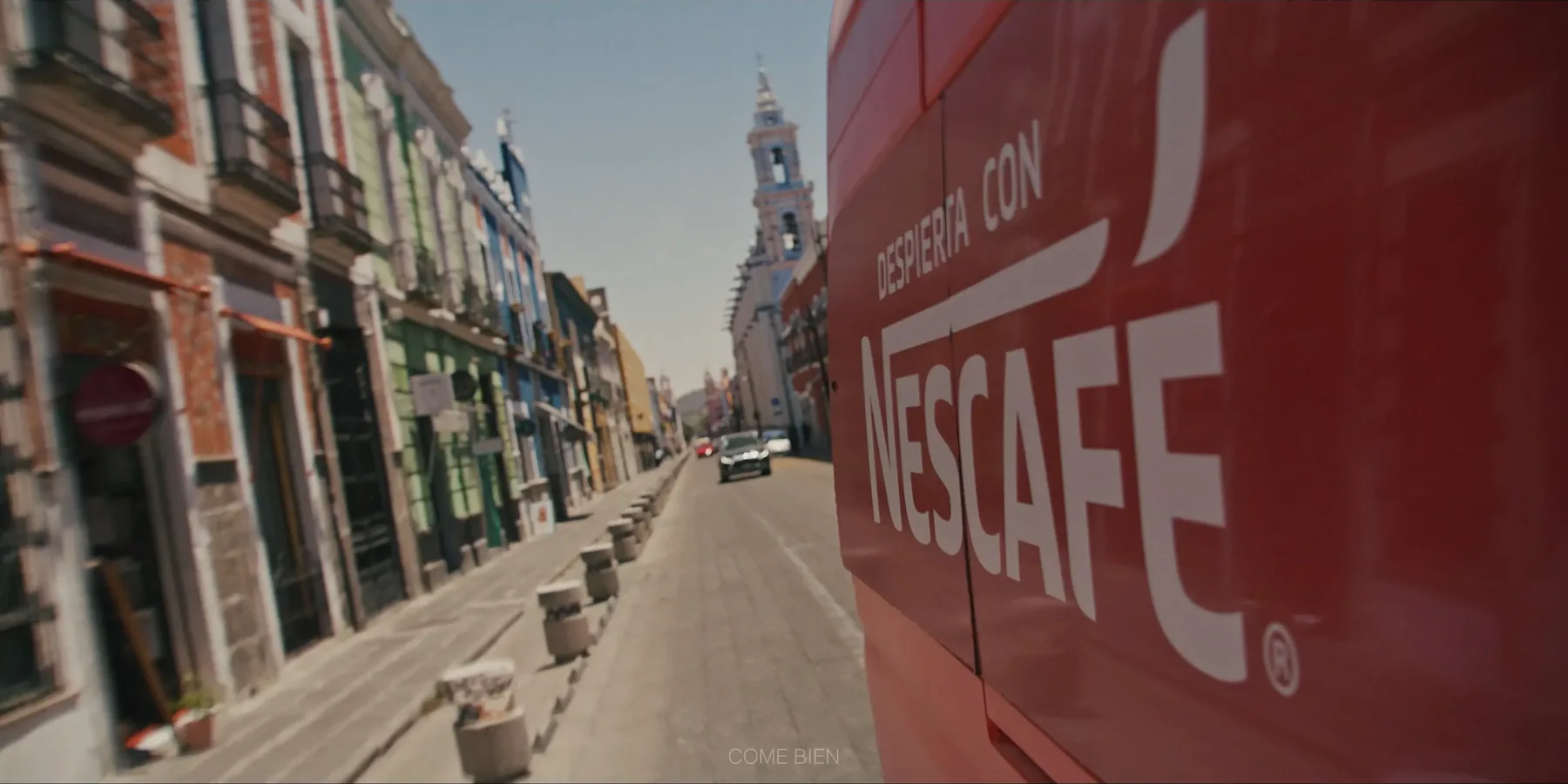 Camión de Nescafé recorriendo una calle colonial